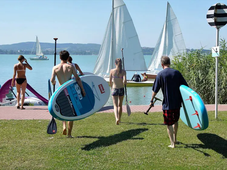 A group carrying SUP boards to the water.